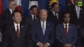 a man in a suit and tie is standing in front of a flag .
