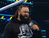 a man with dreadlocks is holding a microphone while wearing a black hoodie with a wolf on it