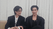 two men in suits are sitting next to each other and talking .