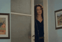 a woman in a black shirt is standing in a doorway next to a framed picture