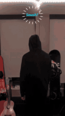 a person in a black hoodie is standing in a room with a smash sign above them
