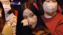 a group of people wearing face masks are sitting in a crowd .