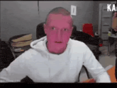 a man in a white hoodie with a pink face is sitting in front of a computer screen .