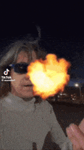 a man wearing sunglasses has a heart shaped fireball coming out of his mouth ..