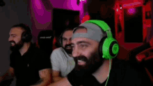 three men with beards are wearing green headphones and smiling .