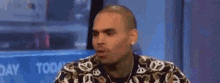 chris brown is wearing a floral shirt and making a funny face on a television show .