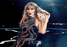 a woman in a black dress is standing on a stage holding her hair