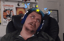 a man wearing headphones looks up at a cuphead poster on the wall
