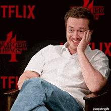 a man sitting in front of a stranger things poster