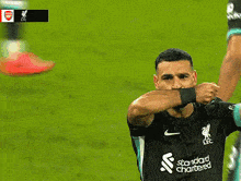 a soccer player wearing a black shirt that says ' liverpool ' on it