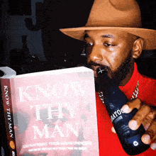 a man is drinking from a bottle while reading a book titled know thy man