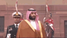 a man in a traditional arabic dress is standing next to a man on a horse .
