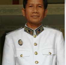 a man in a white uniform with gold buttons has a badge on his collar that says ' a ' on it