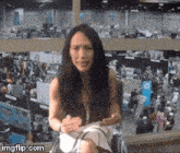 a woman is sitting in front of a crowd at a convention with imgflip.com at the bottom of the image