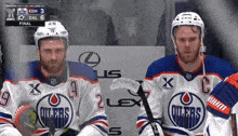 two edmonton oilers players sit in the stands during a game