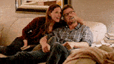 a man and a woman are sitting on a couch looking at something