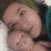a woman with green hair is laying in bed with a doll .