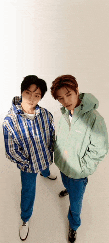 two young men standing next to each other wearing jackets