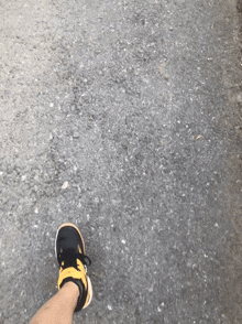 a person 's foot wearing a pair of black and yellow sneakers