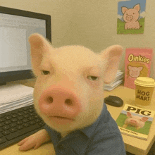 a pig is sitting at a desk in front of a computer with a bag of oinkies in the background