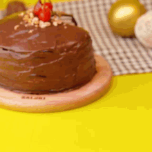 a chocolate cake with cherries and nuts on top is on a wooden cutting board .