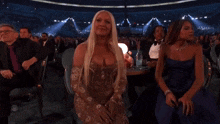 a woman with long blonde hair is sitting in a crowded stadium