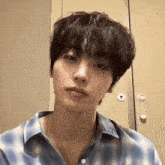 a close up of a young man 's face wearing a blue plaid shirt .