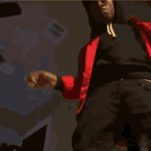 a man in a red jacket is smoking a cigarette in a dark room .