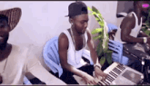 a man in a hat is playing a keyboard while another man sits in a chair .