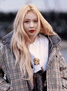 a blonde woman wearing a plaid jacket and a louis vuitton purse