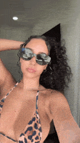 a woman wearing a bikini and sunglasses takes a selfie