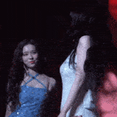 two women are standing next to each other in a dark room