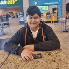 a boy sits at a table in front of subway