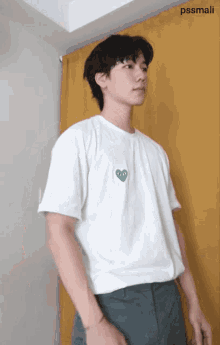 a man wearing a white shirt with a green heart on it