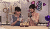 two girls drinking coffee in a kitchen with balloons that say happy birthday