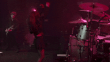 a man playing a guitar and another man playing drums in a dark room