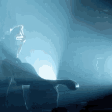 a person is dancing on a stage in a dark room with a blue light behind them .
