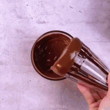 a person is pouring chocolate into a glass on a table .