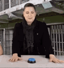 a woman is sitting at a table with a blue button on it