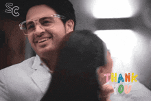 a man wearing glasses is hugging a woman and the words thank you are visible