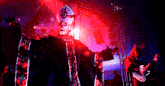 a man in a priest costume is singing into a microphone while another man plays guitar