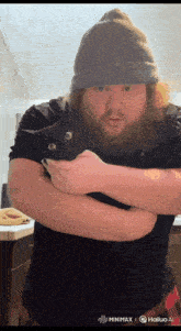 a man with a beard is holding a black cat in his hands
