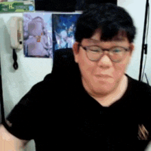 a man wearing glasses and a black shirt is looking at the camera .