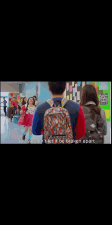 a man with a backpack is walking down a hallway with a girl behind him