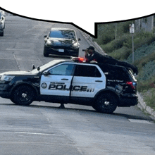 a police car is driving down a street with a man on top of it