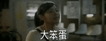 a woman is smiling in a dark room with chinese writing on the wall behind her .