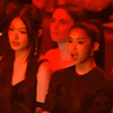 a group of women sitting in a dark room with red lights