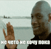 a man is smiling and waving his hand in front of a sign that says he cheto he xoy poka