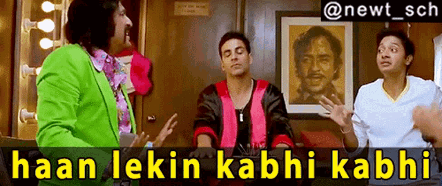 a man in a green jacket is talking to two other men in front of a painting that says haan lekin kabhi kabhi