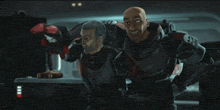 two men in armor are standing next to each other in a room .